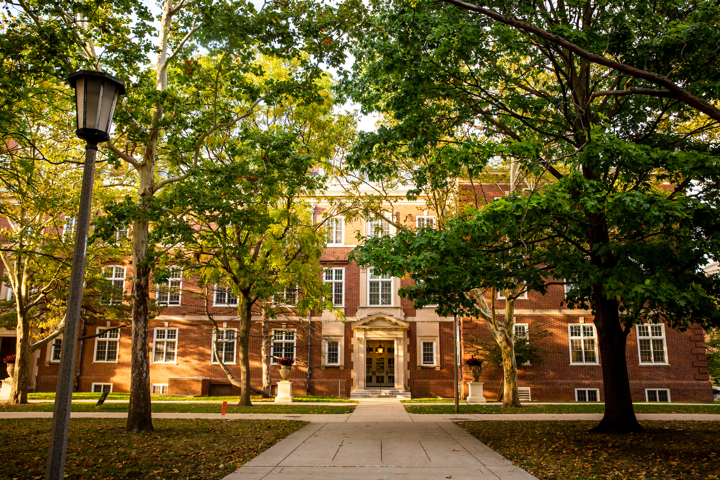 A historic academic building on a college campus, shaded by trees